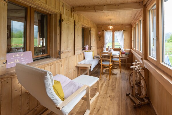 Interior de una cabaña de madera con un banco, una mesa y un rueca.