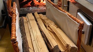 A wood stove with logs inside, a white cabinet, and a tiled wall. - Rosenhaus 3 (Schwarzenberg)