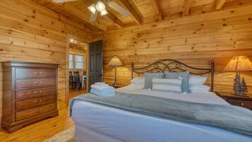 A wooden cabin bedroom with a bed, dresser, and ceiling fan.