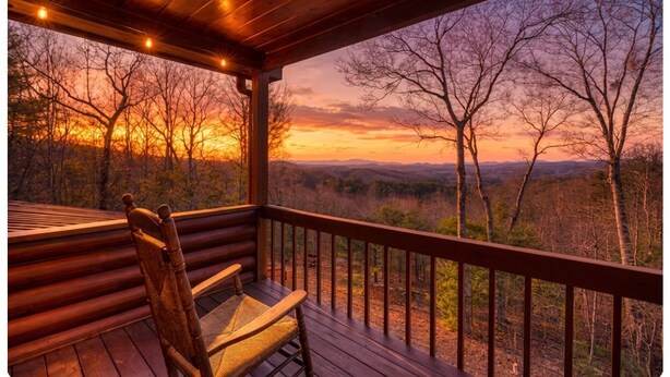 A wooden deck with a chair, overlooking a forested landscape during sunset. - Hidden Hills, Cabin for Family Getaway with Mountain Views! - Hot Tub and Wifi (Blairsville)