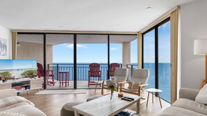 Un vaste salon avec un balcon donnant sur la mer, aménagé avec des fauteuils et un canapé modernes.