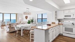 Une cuisine moderne avec des meubles blancs, un îlot central et une vue sur l’océan.