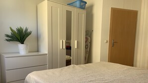 A bedroom with a bed, a wardrobe, a potted plant, and a door. - Quiet apartment on the outskirts of the city (Chemnitz)