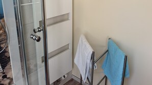 A bathroom with a glass shower door, a towel rack, and a wooden floor. - Quiet apartment on the outskirts of the city (Chemnitz)