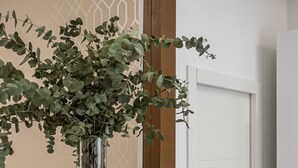 Un meuble blanc surmonté d’un vase en verre contenant des feuilles vertes.