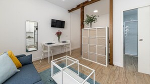 Un salon moderne comprenant un canapé, une table basse en verre, une table à manger avec des chaises, un téléviseur fixé au mur et une porte coulissante.