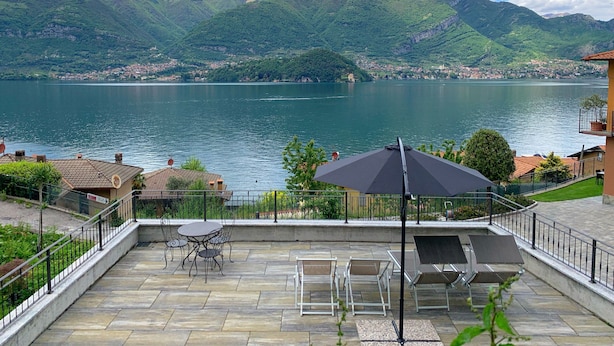 Une terrasse meublée, donnant sur un lac et des montagnes.