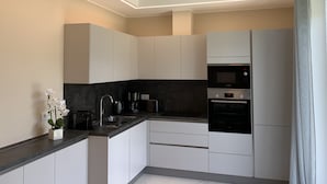Une cuisine moderne avec des meubles blancs, un four Bosch et un plan de travail noir.