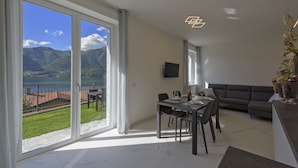 Un salon moderne avec un coin repas, de grandes portes-fenêtres coulissantes donnant sur un balcon avec vue sur le lac.