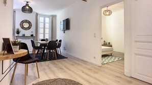 Una sala de estar moderna con comedor, piso de madera y un ventanal grande.