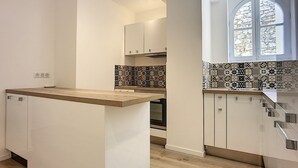 Una cocina moderna con armarios blancos, encimera de madera y azulejos decorativos en la pared.