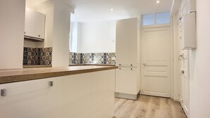 Una cocina moderna con muebles blancos, encimera de madera y azulejos decorativos en la pared.