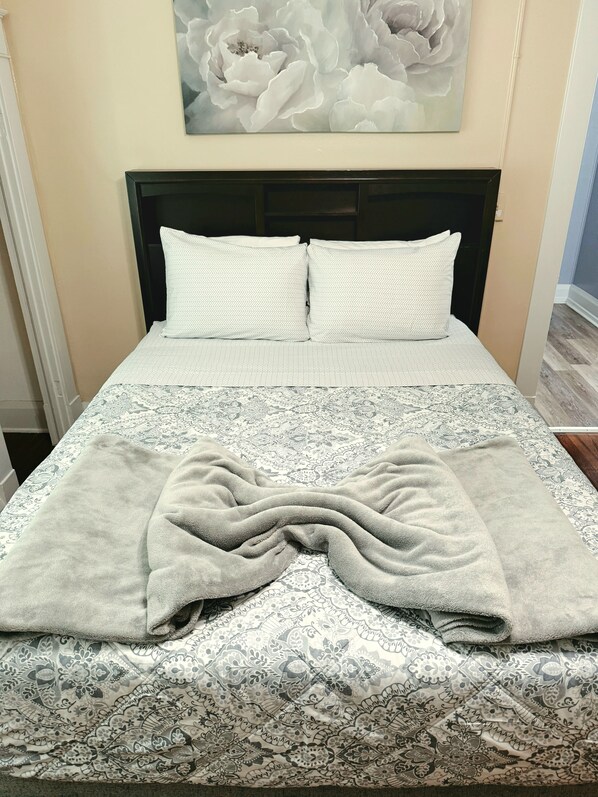 Un lit avec une couvre-lit à motifs, deux oreillers et une couverture.