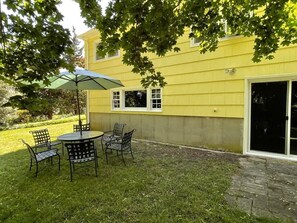 A yellow house with a patio, a table with chairs, and a large umbrella.