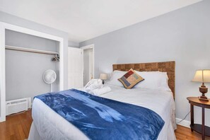 A hotel room with a bed, bedside table, lamp, and a walk-in closet.