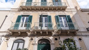A multi-story building with balconies, a central entrance with an ornate arch, and a number '55' on the facade. - Ortigia: A luxury apartment by the sea (Syracuse)