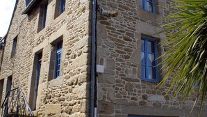 A stone building with a staircase leading to the entrance, a metal railing, and a signboard in front. - Maison au Coeur de Moncontour (Moncontour)