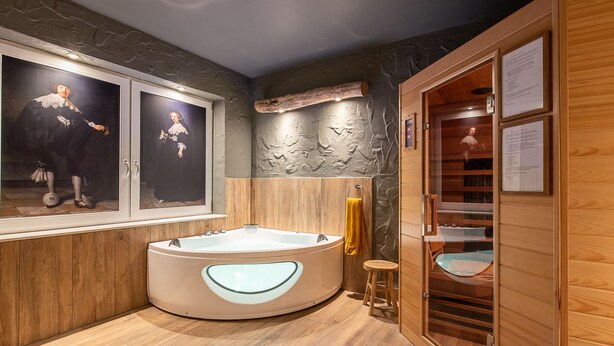 Une salle de bain moderne avec une baignoire sur pieds, un lambris en bois et des œuvres d’art accrochées aux murs.