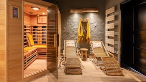 Un sauna avec des bancs en bois, un banc sur lequel est posée une serviette jaune, et un porte-serviettes fixé au mur, avec des serviettes.