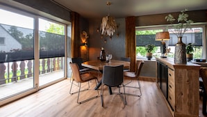 Un espace repas moderne avec une table en bois, des chaises et un luminaire suspendu.