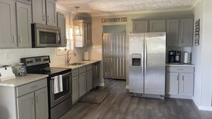 Une cuisine avec des meubles gris, des appareils en acier inoxydable, un four à micro-ondes, une cuisinière et un réfrigérateur.