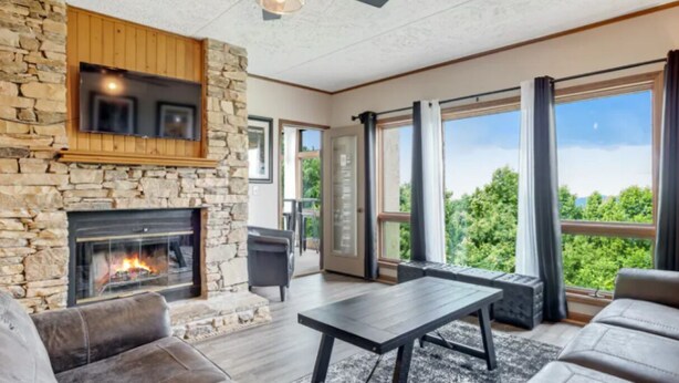 A living room with a stone fireplace, large windows, and a view of greenery.