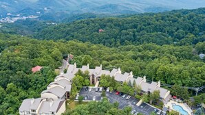 An aerial view of a residential area with a cluster of houses, a parking lot, and a swimming pool.