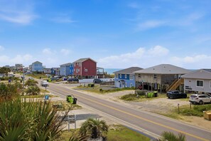 Una carretera costera bordeada de casas coloridas, algunas con entradas y coches aparcados.