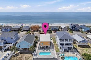 Un quartier résidentiel en bord de mer, avec des maisons, une piscine et une plage en arrière-plan.