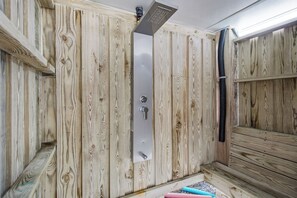 Un sauna con paredes de madera, una puerta metálica y un cabezal de ducha.