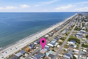 Zona residencial costera con playa, casas y una carretera.