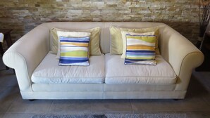 A beige sofa with two pillows against a stone wall. - Azenhas do Mar Village - Holiday Rentals (Colares)