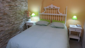 A bed with a patterned bedspread, two pillows, and two bedside tables with lamps. - Azenhas do Mar Village - Holiday Rentals (Colares)