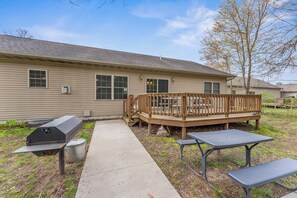 A building with a deck, a barbecue grill, and picnic tables. - First Class "ARCADE" /18 PERSON/3400 sq ft/10 Bed/Firepit/HUGE kitchen/Fireplace (Wisconsin Dells)
