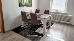 Spiseområde med bord, stole, et billede på væggen, et vindue og en radiator.
