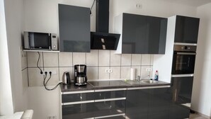 Et moderne køkken med sorte skabe, en mikrobølgeovn, kaffemaskine og et indbygget ovn.