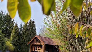 Eine Holzhütte mit geneigtem Dach, umgeben von einem gepflegten Rasen und dichten Bäumen.