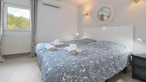 A bedroom with a large bed, two wall-mounted lamps, a round mirror, and a window with curtains. - Wunderschönes Apartment mit Meerblick (Benissa)
