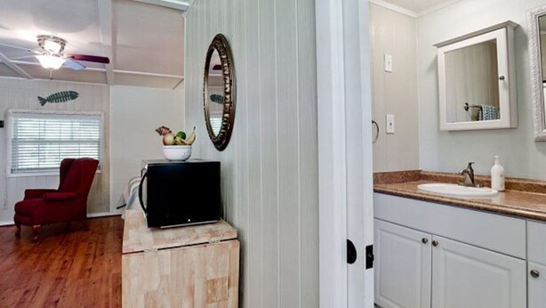 A compact living space with a wooden cabinet, a red chair, a television, a white sink, and a mirror. - Ty's Canal Cottage  (Cortez)