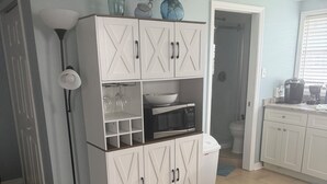 A kitchen with white cabinetry, a microwave, and a coffee maker on the counter. - Ty's Canal Cottage  (Cortez)