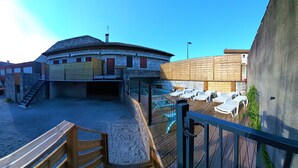 A courtyard with a stone building, wooden deck, and outdoor seating.