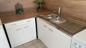 A modern kitchen with white cabinets, a stainless steel sink, and a built-in oven.