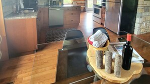 A spacious kitchen with wooden beams, a stone wall, and a modern stainless steel refrigerator. - Your Home Away From Home (Perth)