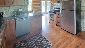 A spacious kitchen with wooden beams, a stone fireplace, and a large island. - Your Home Away From Home (Perth)