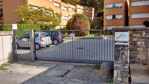 Un parking clos, avec plusieurs voitures, un mur en pierre et un panneau indiquant qu’il s’agit d’un système de stationnement automatisé.