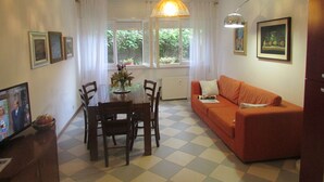 Un coin repas avec une table et des chaises, un canapé et une fenêtre avec des rideaux.