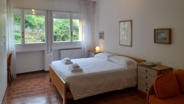 Une chambre à coucher comprenant un lit, une chaise, une table de chevet et un ventilateur de plafond.