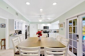 A spacious kitchen with white cabinets, a dining table with chairs, and a ceiling fan.