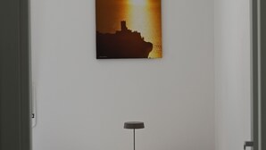 A room with a white wall, a round table with a black lamp, and an orange chair. - MODERN APARTMENT SECOND FLOOR AND PARKING SPACE APP SOLE (Malcesine)