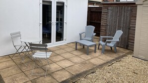 Un espace patio avec un mur blanc, une porte-fenêtre coulissante et une clôture en bois.